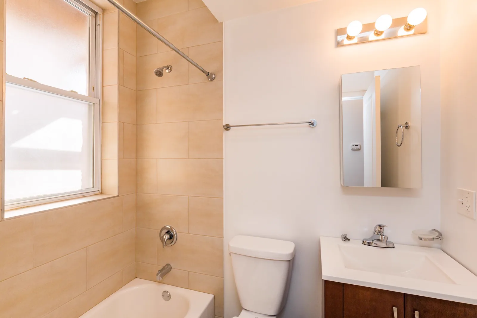 Bathroom with window, tiled tub surround and vanity